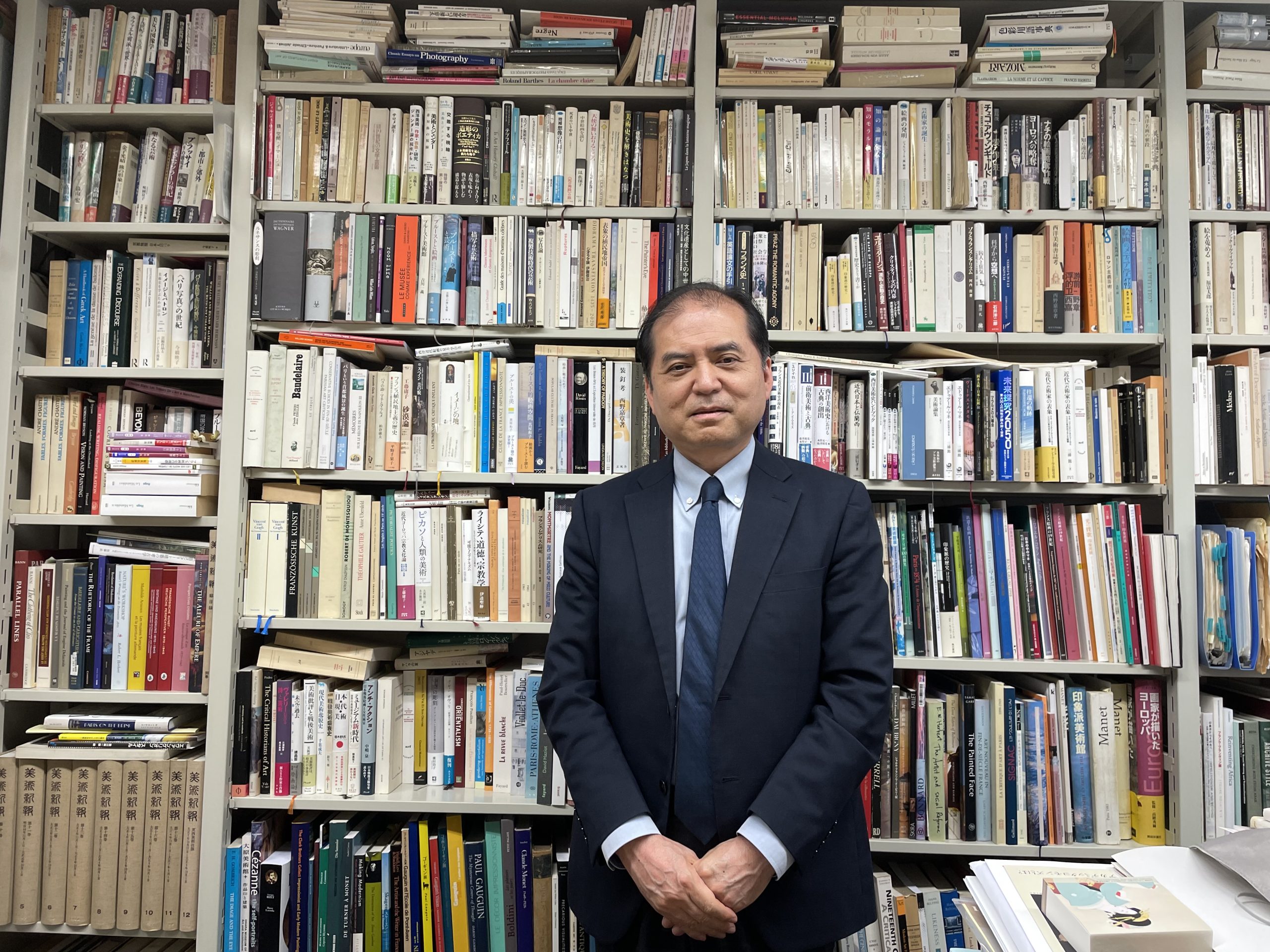 三浦篤教授　駒場の研究室にて、書棚を前に