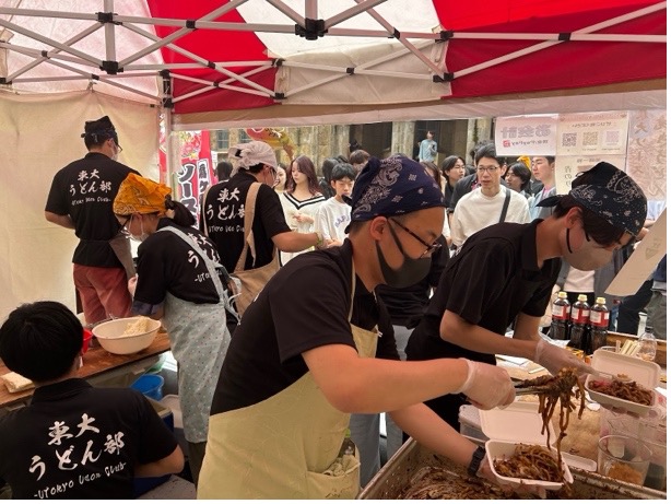 うどん部のテントの様子。エプロンをつけた部員がせっせと調理している